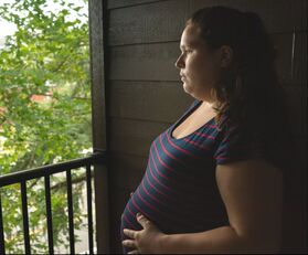 Photo of pregnant person looking out over a balcony